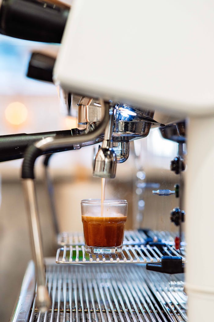 High-quality close-up of an espresso machine brewing coffee into a glass cup in a café setting.