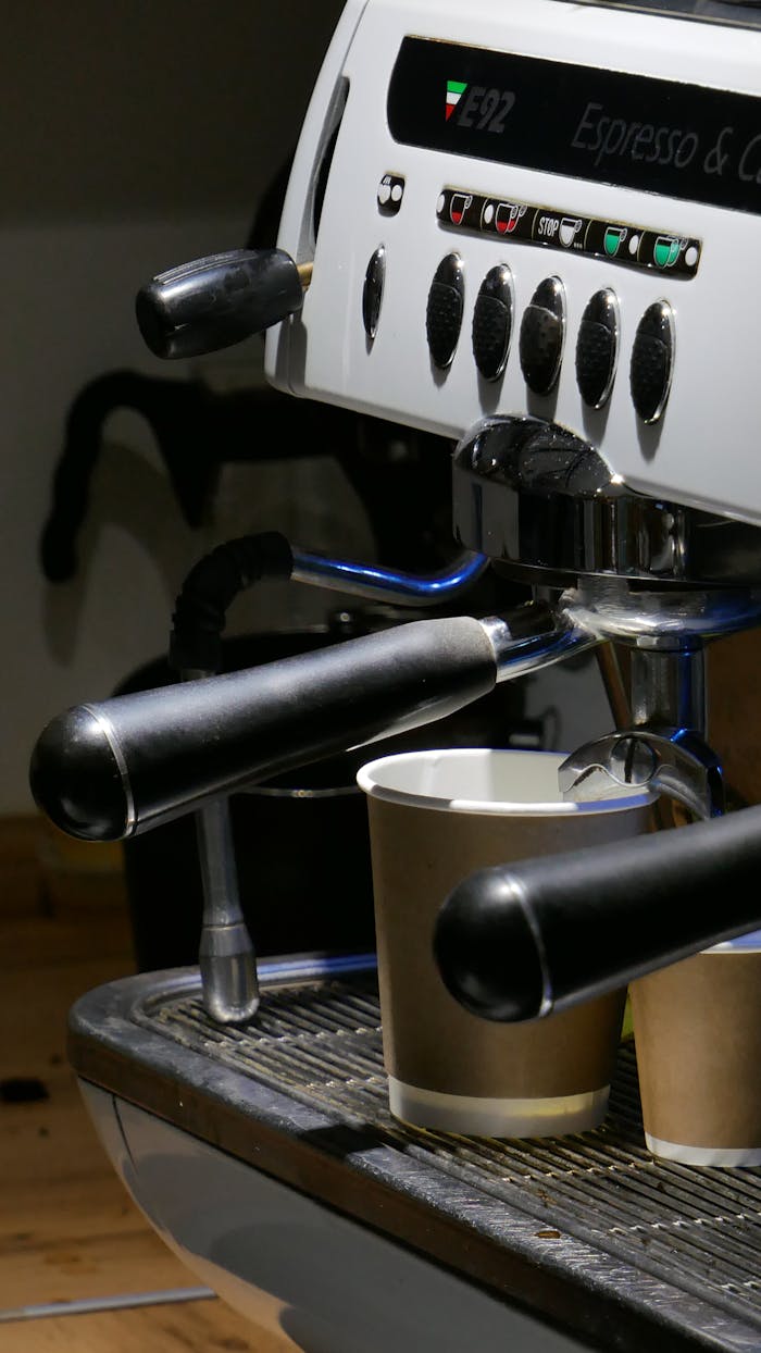 Close-up of a professional espresso machine brewing into cups in a café environment.