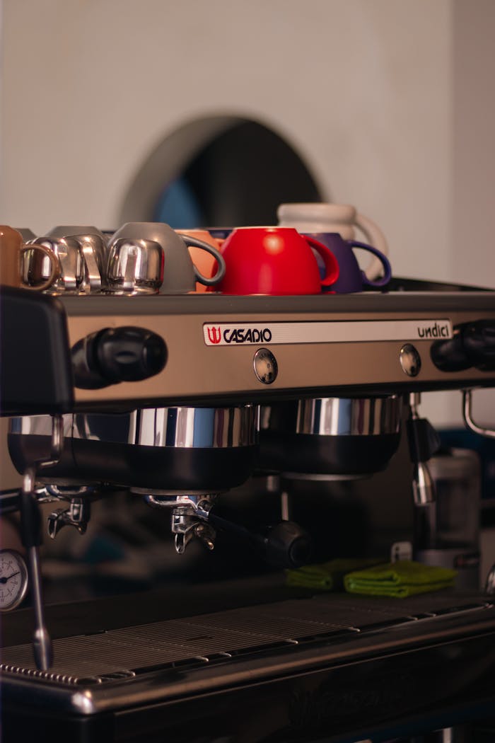 Espresso machine with colorful cups on top, ideal for coffee shop visual content.