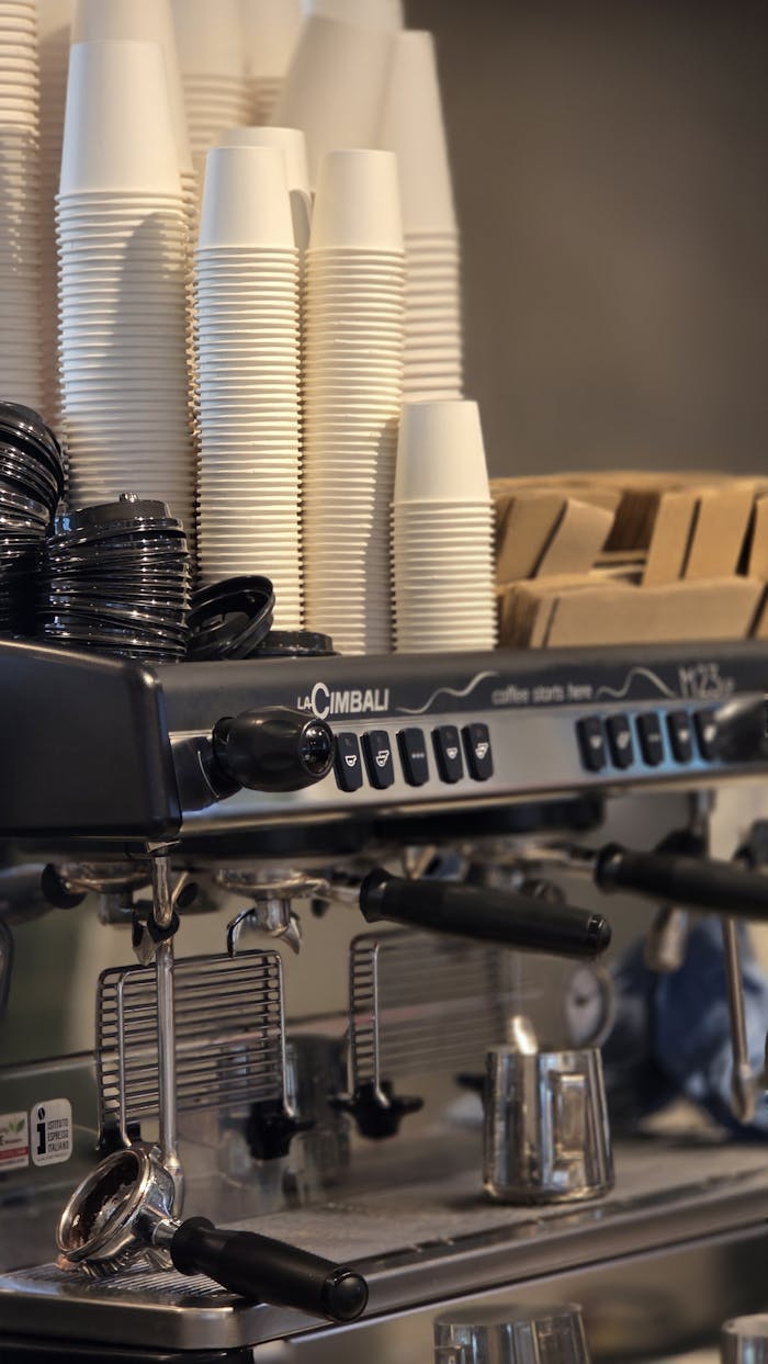 Close-up of a modern espresso machine with stacked cups in a café ambiance.