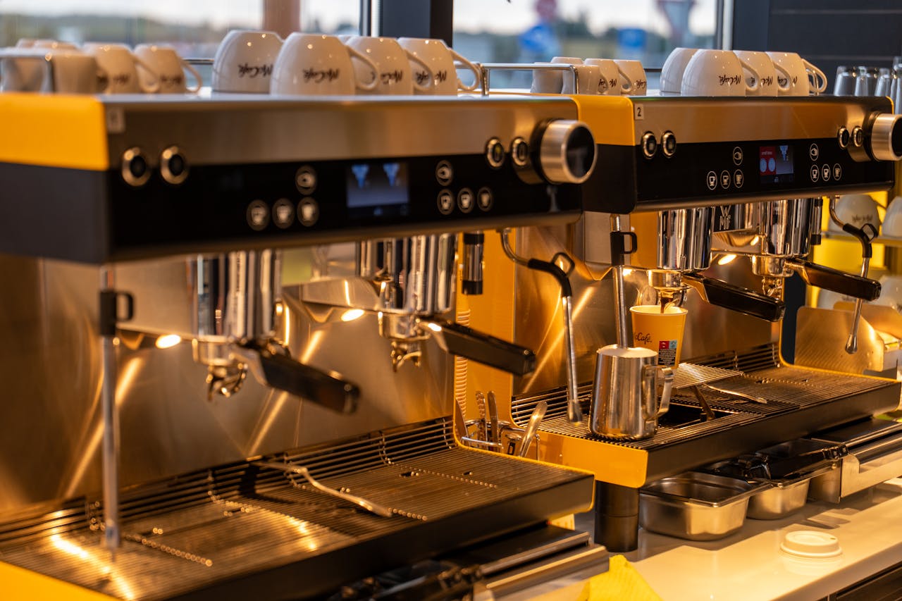 A pair of advanced espresso machines in a warm-lit, inviting cafe in Osijek.
